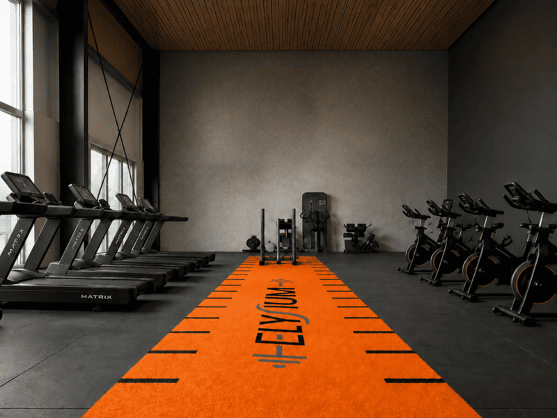 Commercial indoor gym facility featuring a vibrant green SPU backed turf sled track lane